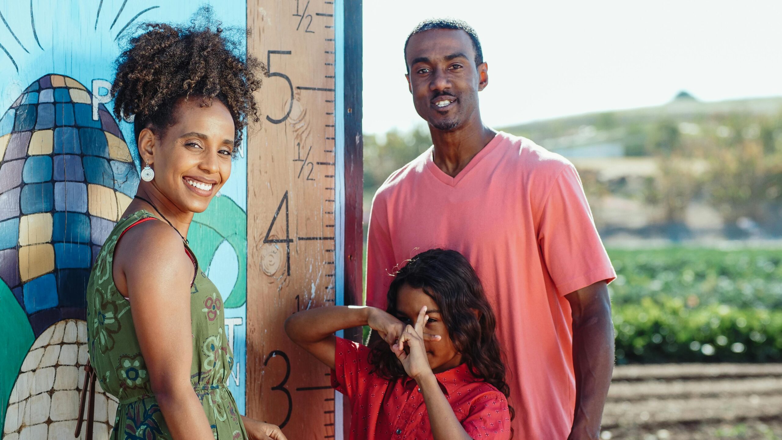 Smiling family enjoying a sunny day outdoors near a painted mural.